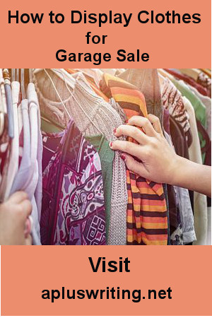 Clothes hanging on a clothes rack with customers hand sorting through them