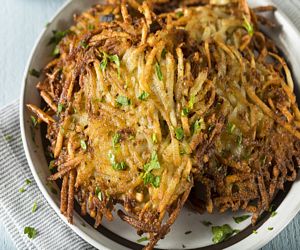 A plate of potato latkes garnished with sliced green onions