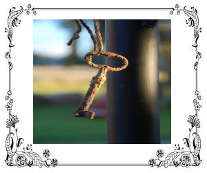 Rusty key hanging by a thread.