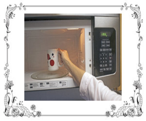 A woman putting a cup into a microwave oven
