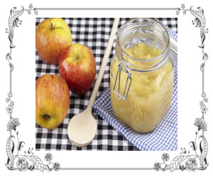 Jar of applesauce with spoon and fresh apples