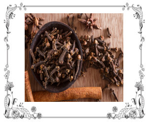 Small dish of whole cloves and cloves lying on a tabletop.