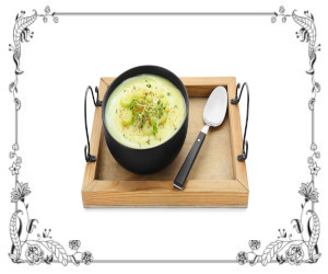 Bowl of broccoli soup with spoon on a serving platter.